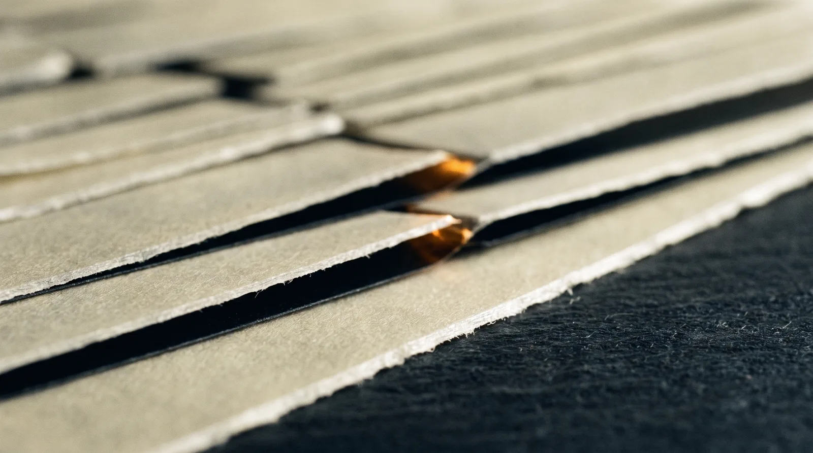Macro photograph of layered paper edges with a narrow lit gap between two of them.