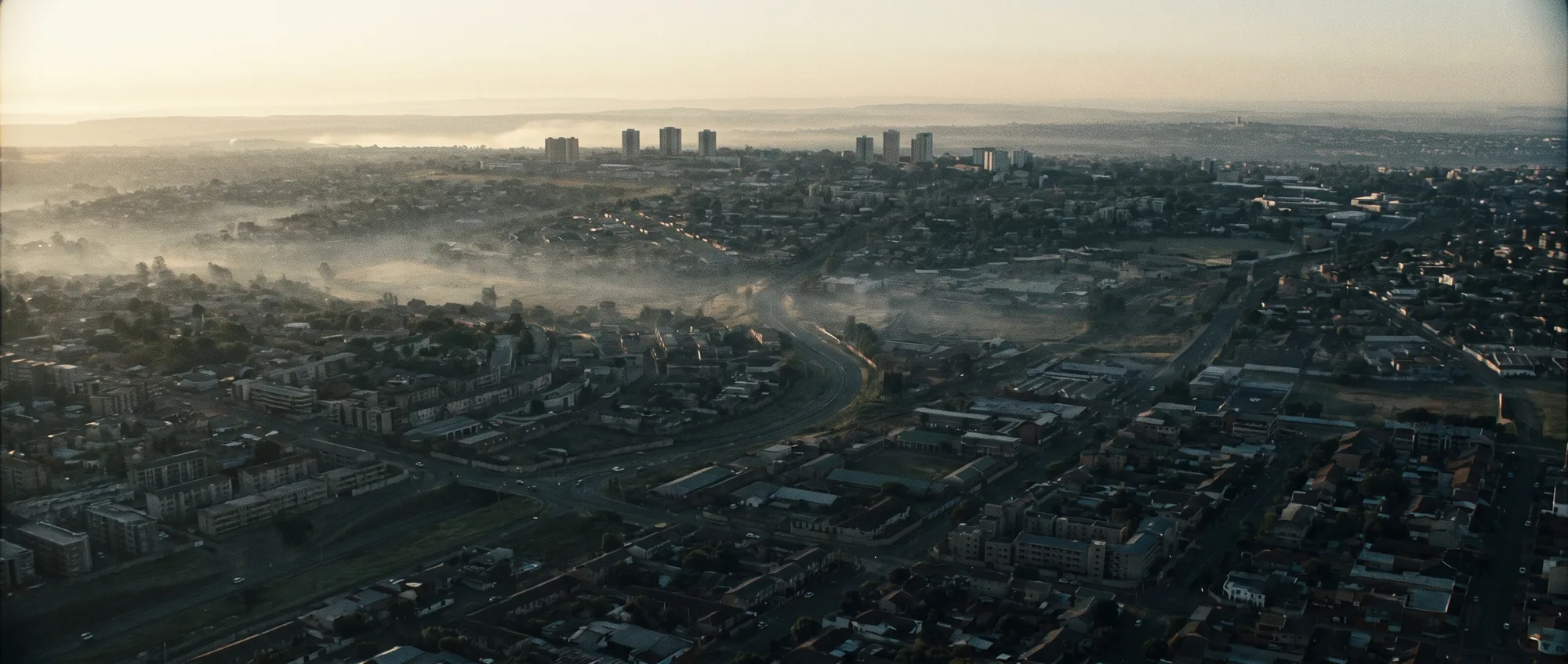 Aerial view of a South African city at first light, mist lying between the tower blocks.
